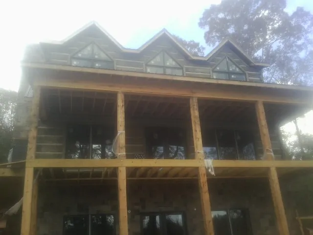 Dormers and porch framing on a large log home under construction — Roof Coating work by our crew in Montgomery